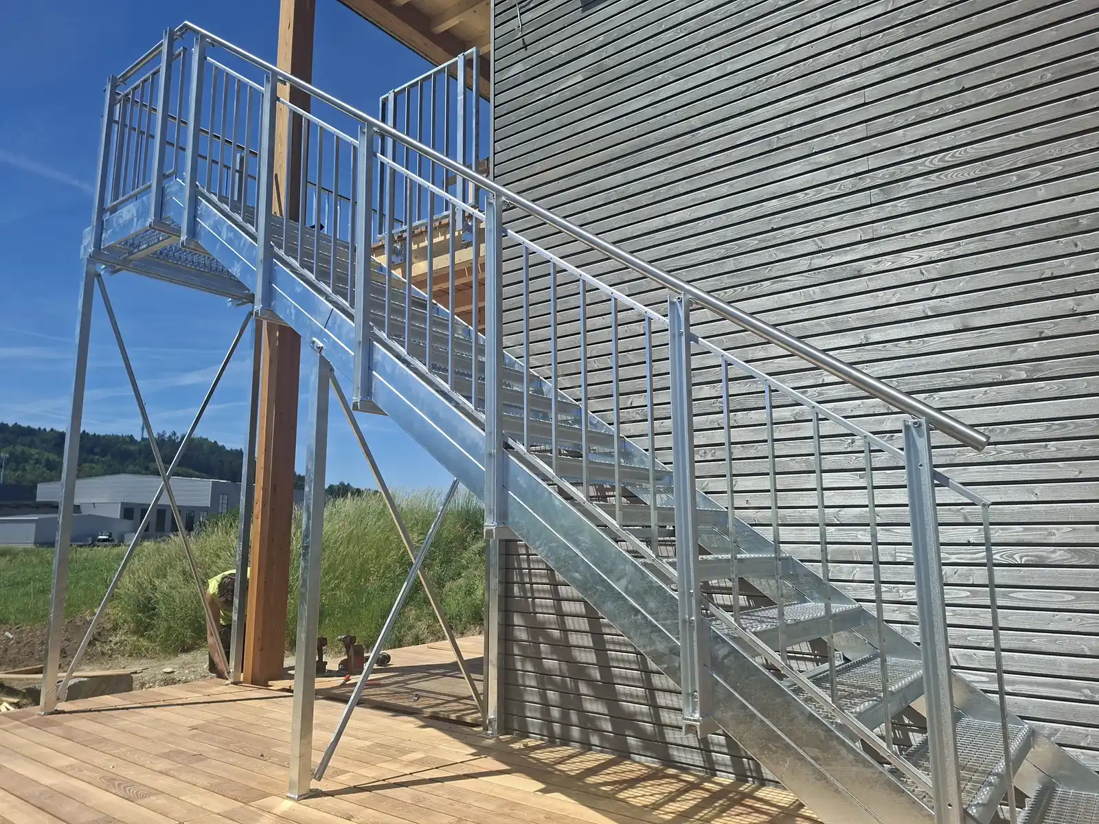 Aussentreppe an einer Holzfassade mit Staketengeländer Flex, feuerverzinkter Stahl, Geländer folgt durchgehend der Treppenneigung